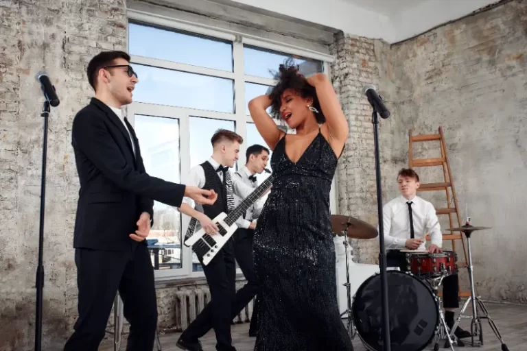 A Boston Band performs in a rustic room; a woman in a black dress sings while three men play guitar, keyboard, and drums—ideal for unforgettable wedding music.